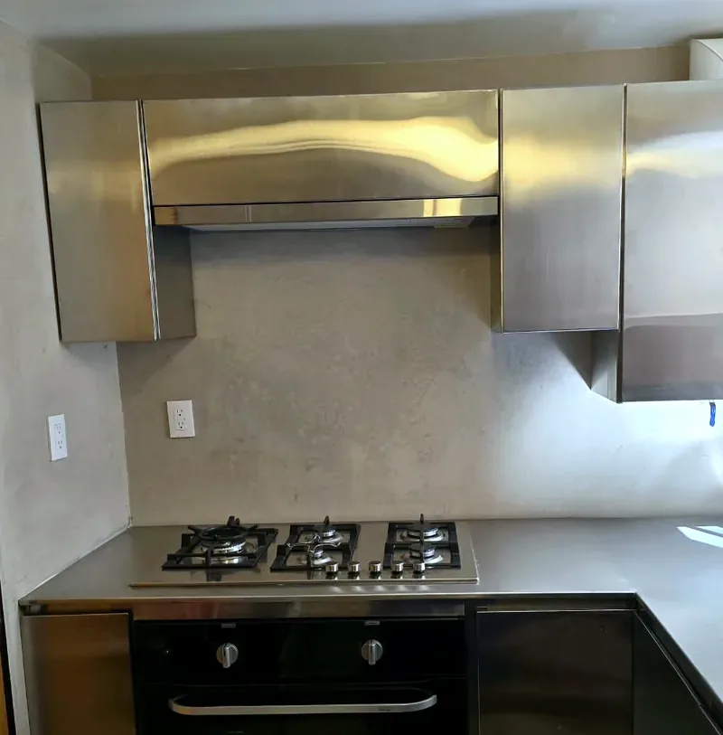 Cocina de acero inoxidable a la medida instalada: alacenas, campana y cubierta de acero inoxidable