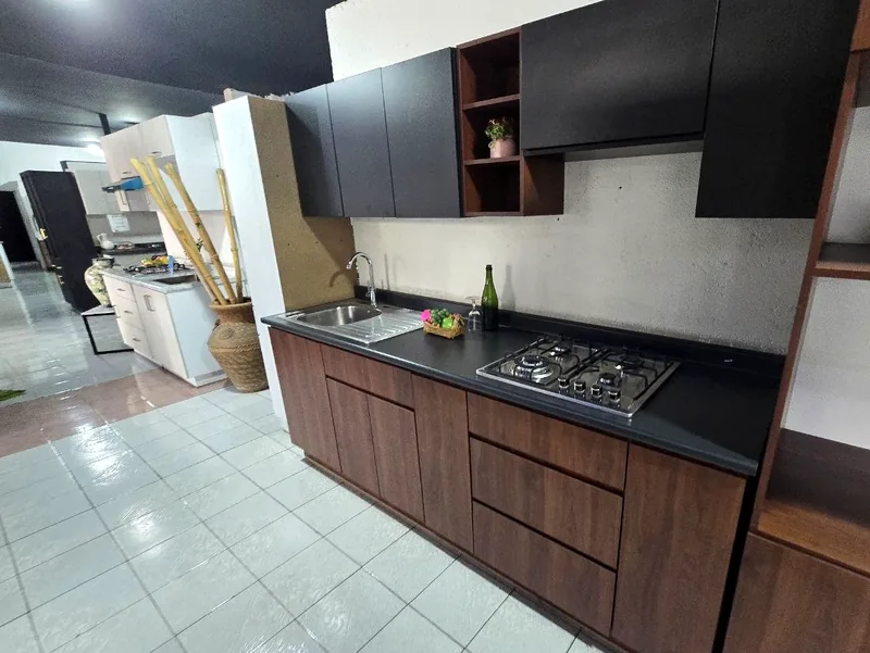Sala de exhibición de Casa Inox: cocina de melamina en nogal y negro, con cubierta oscura y tarja de acero inoxidable